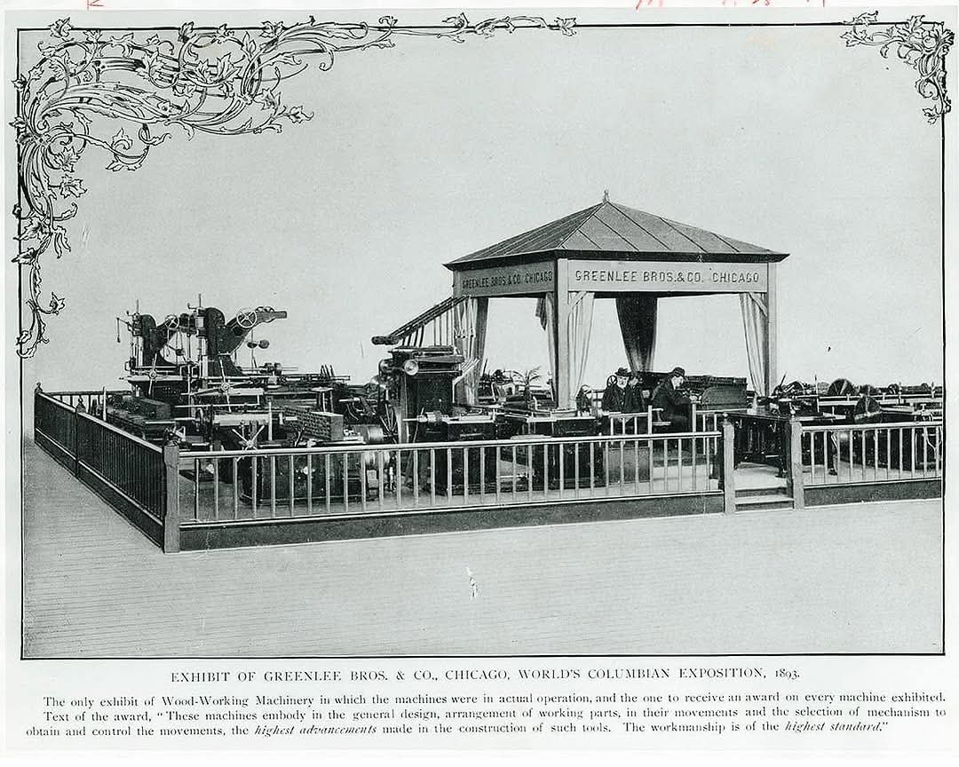 Period photograph of the Greenlee Bros. & Co. exhibit at the 1893 World's Columbian Exposition — rows of machines behind an ornamental railing, beneath a canvas-draped pavilion lettered GREENLEE BROS. & CO. CHICAGO
